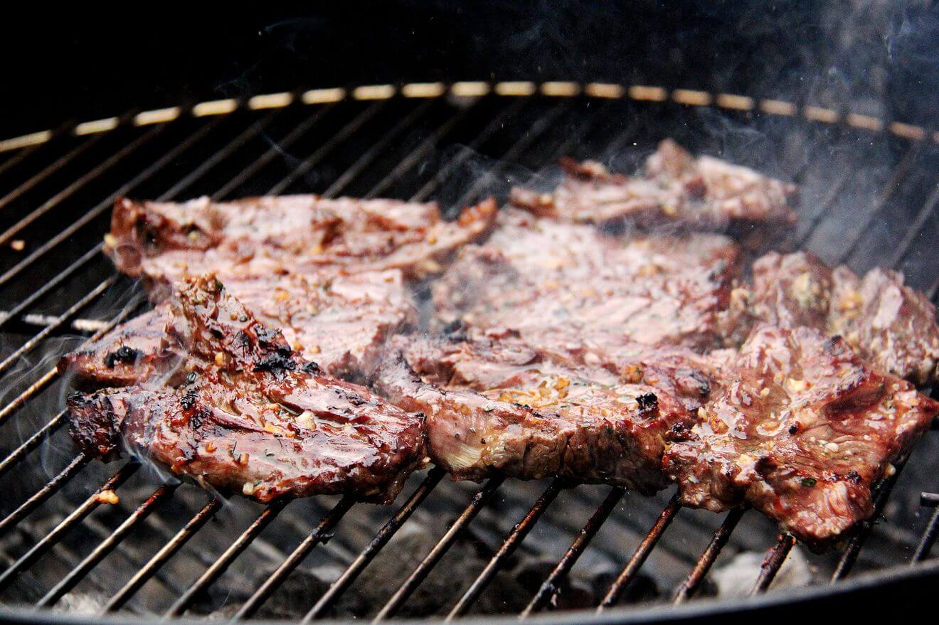 Hanger steaks cooking on the grill. 