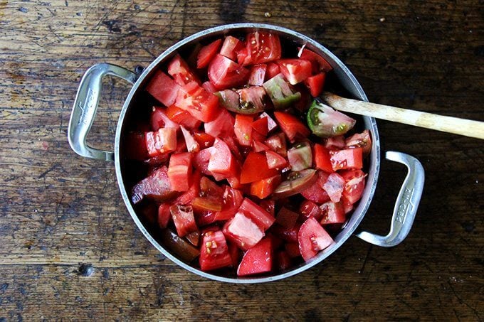 A pot with simmered onions and chopped tomatoes heaped on top. 