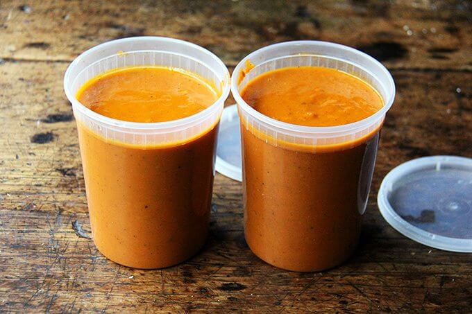 Two quart containers filled with tomato sauce. 