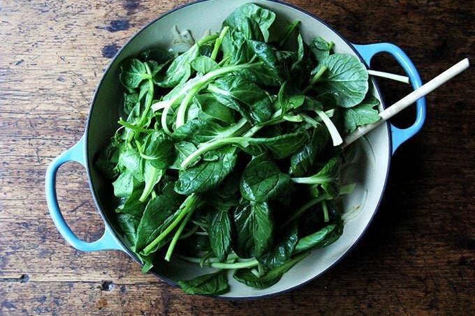 An overhead shot of a skillet filled with greens.