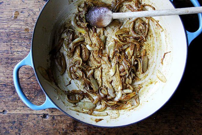 A Le Creuset braiser filled with sautéed onions and ras-el-hanout.