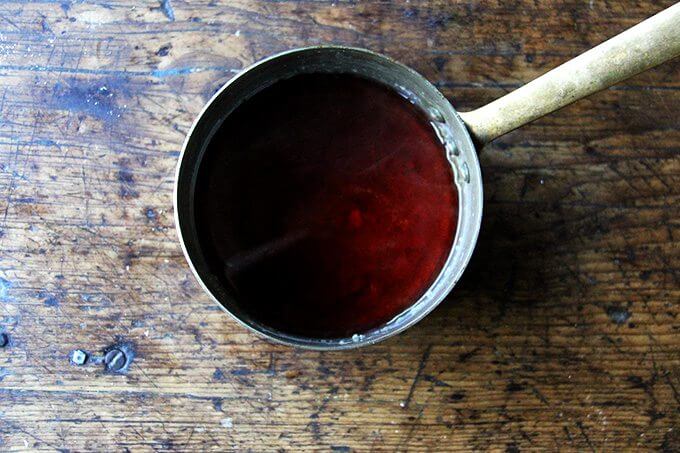 adding the vinegar to a saucepan of caramelizing sugar