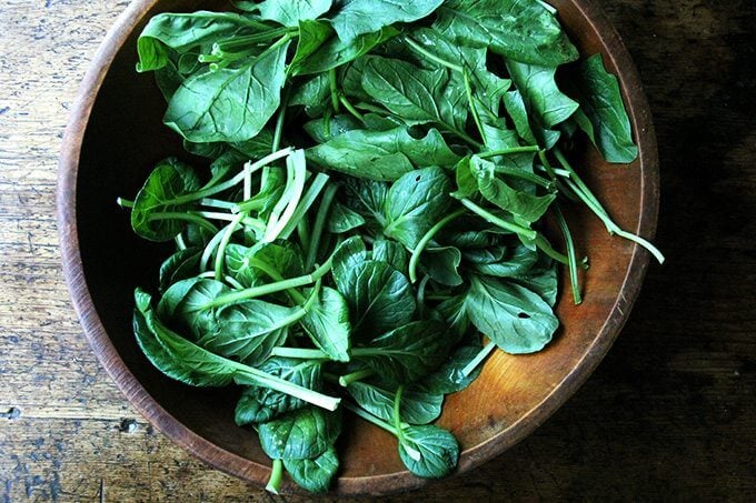 A bowl filled with various dark, leafy greens.