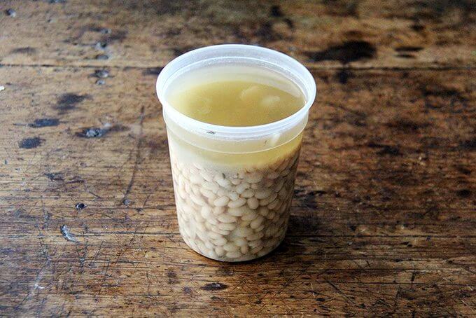 A quart container filled with cooked white beans.