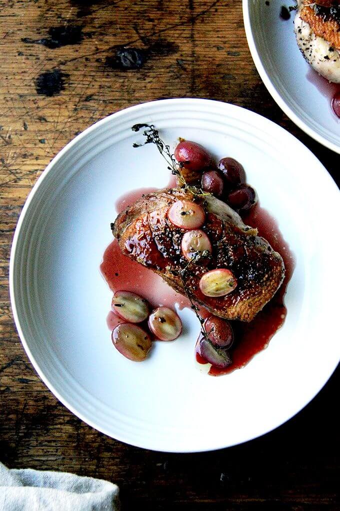 A plate of pan-seared Duck breasts with port wine sauce and roasted grapes. 