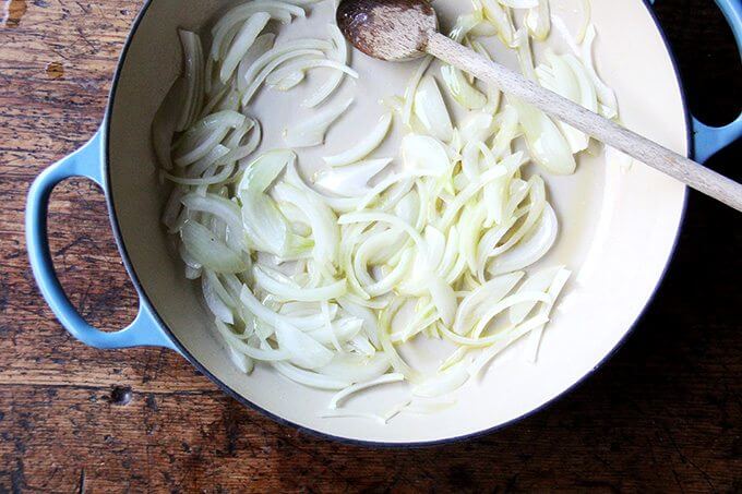 A Le Creuset braiser filled with sautéed onions. 