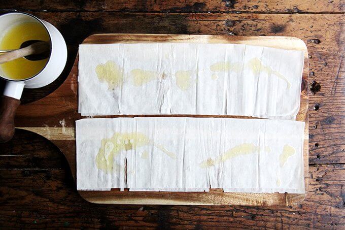 Phyllo on a cutting board, brushed with butter.