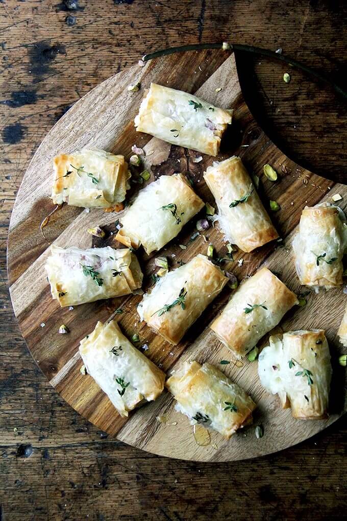 A board filled with salami and provolone phyllo rolls.