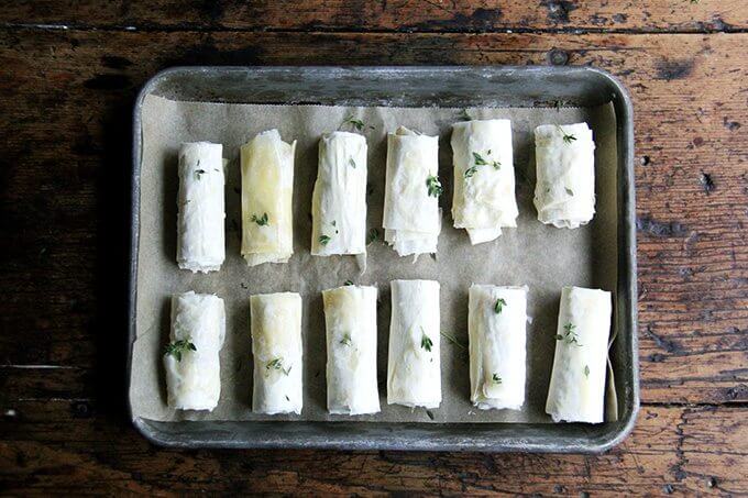 A sheet pan filled with salami and provolone phyllo rolls.