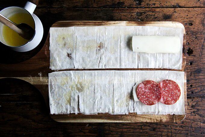 Phyllo on a cutting board, brushed with butter, topped with provolone and salami.