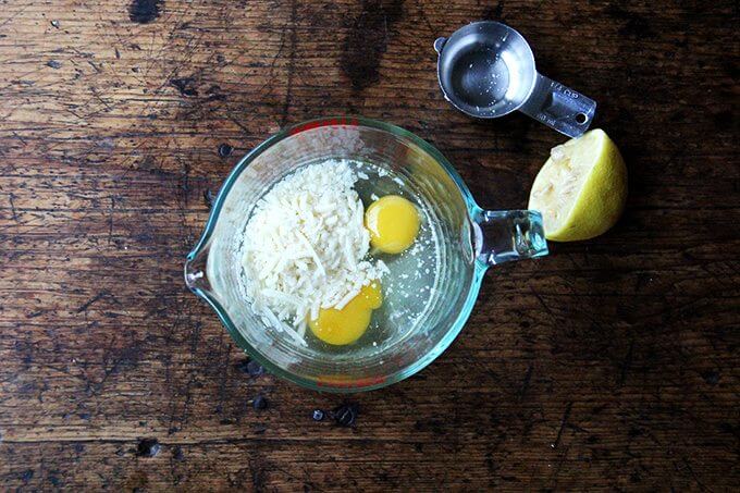A liquid measure filled with parmesan, eggs, lemon, and pasta cooking liquid.