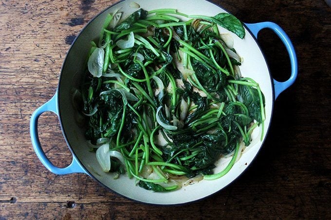 An overhead shot of a skillet filled with sautéed greens.