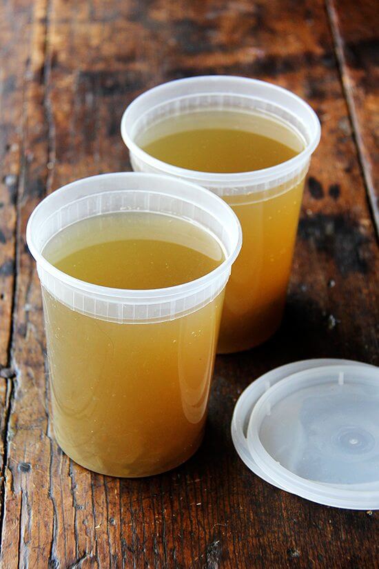 Two quarts of homemade vegetable stock on a table. 