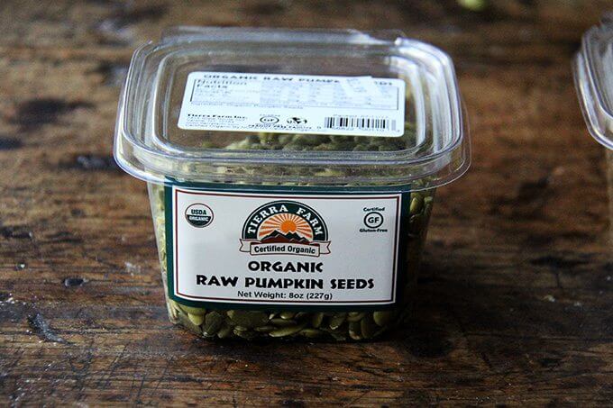 A container of organic, raw, pumpkin seeds.