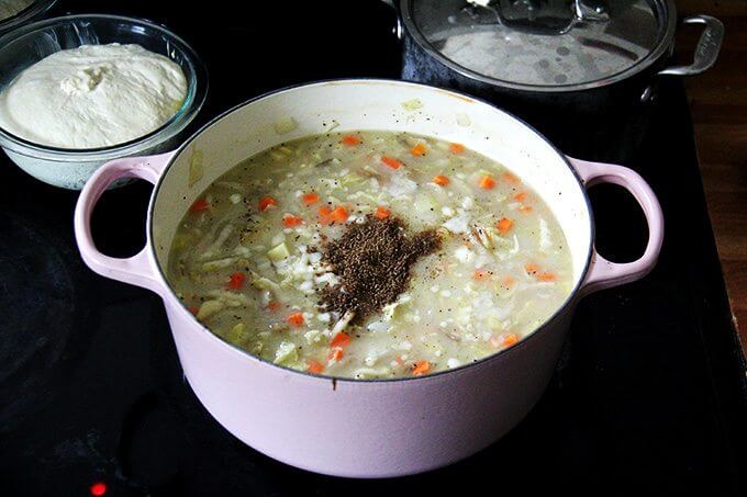 A large pot of vegetarian cabbage soup simmering on the stovetop with caraway added. 