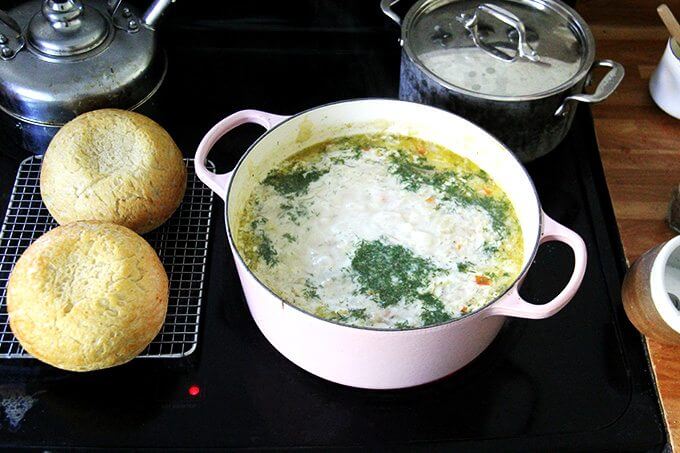 A large pot of vegetarian cabbage soup with heavy cream and dill added aside two loaves of homemade bread. 