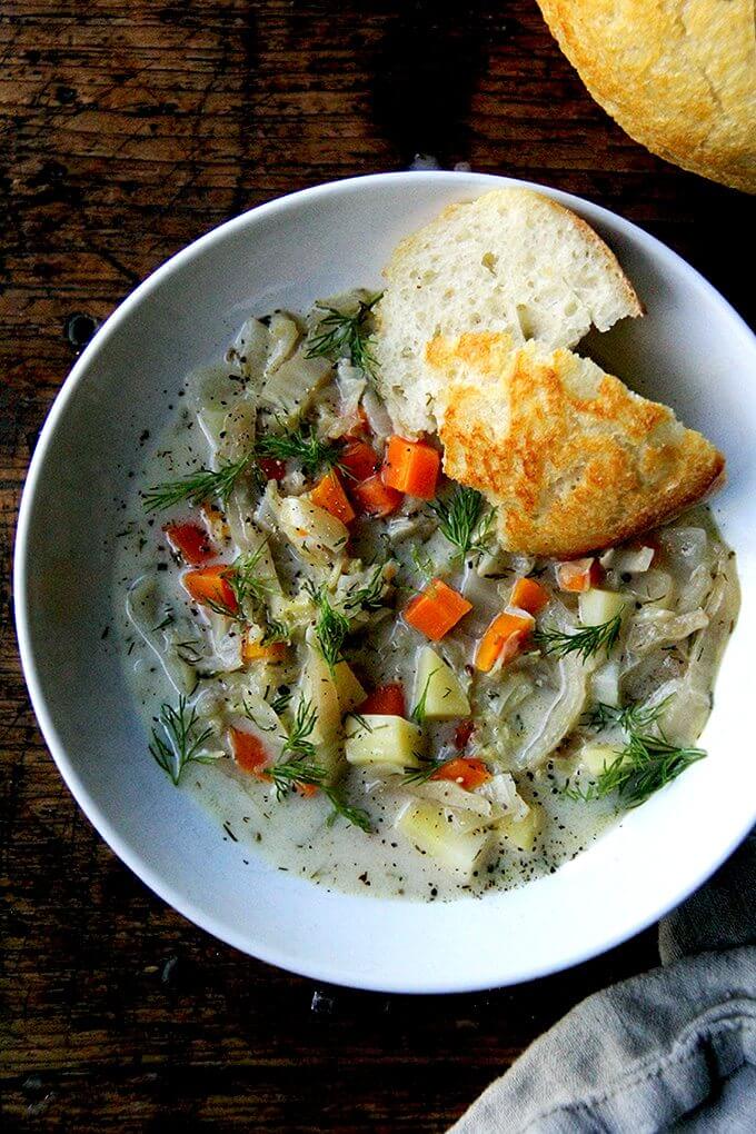 A bowl of cabbage soup with bread in a bowl. 