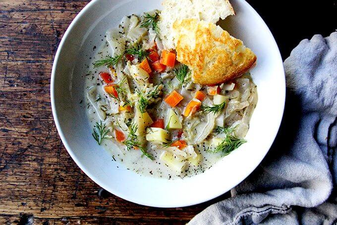 An overhead shot of cabbage soup in a bowl with bread. 