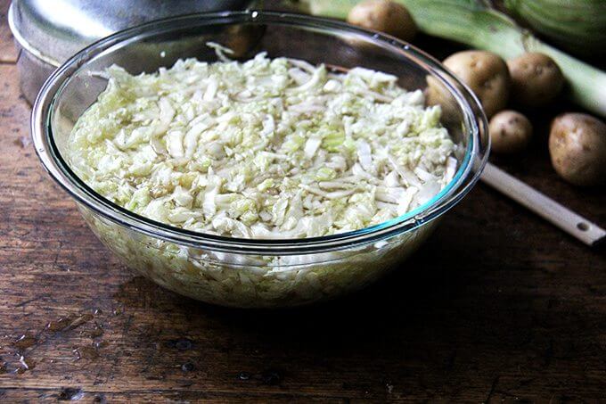 A large bowl filled with sliced cabbage covered in boiling water. 