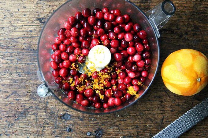 A food processor filled with cranberries and orange zest.