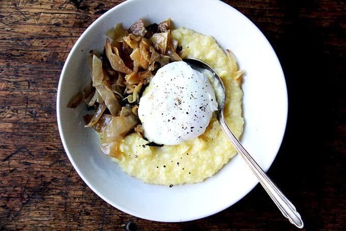 A bowl of polenta, caramelized cabbage, and a poached egg. 