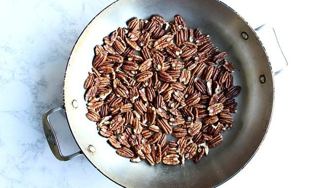 A skillet filled with pecans. 