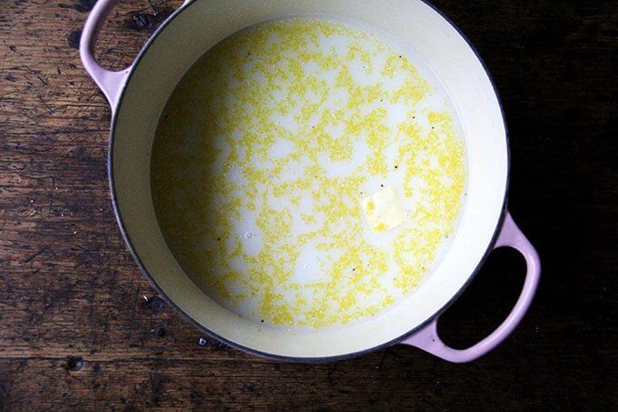 A Dutch oven filled with water, milk, and polenta, ready for the oven.