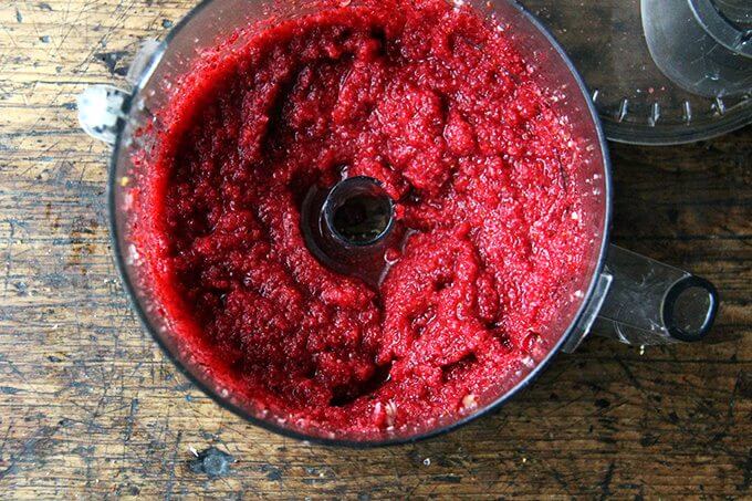 A food processor filled with puréed cranberries, sugar, orange, and zest. 