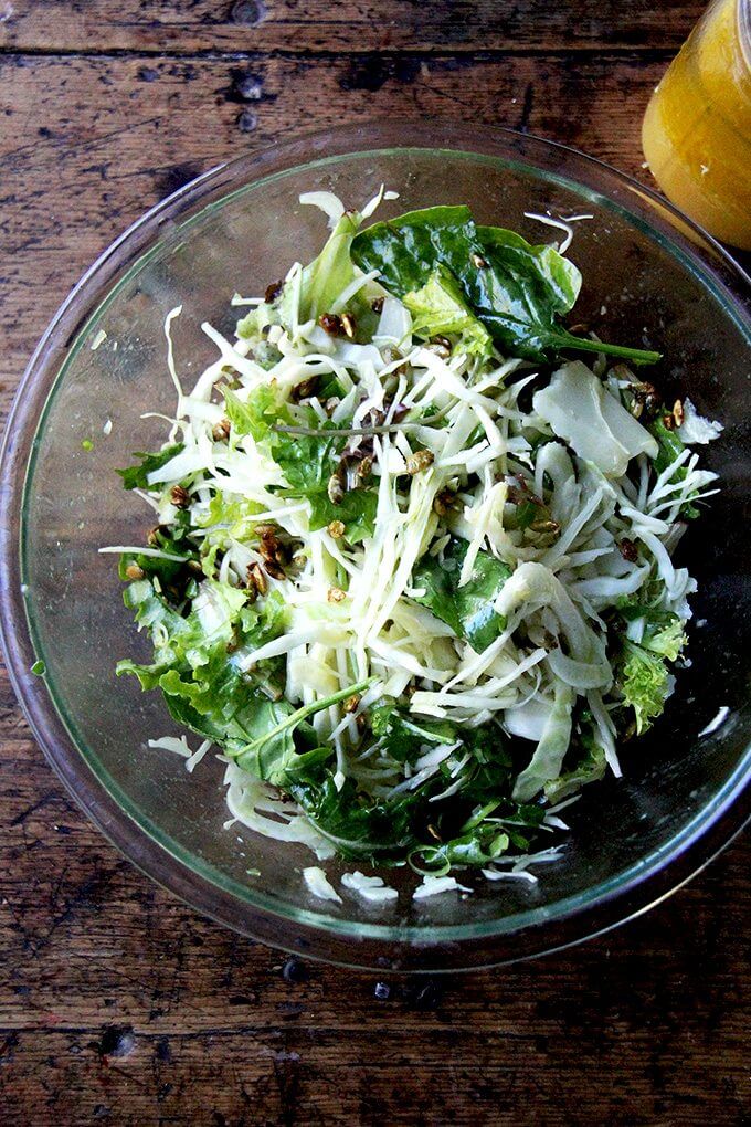 A large bowl filled with fall salad tossed with dressing.