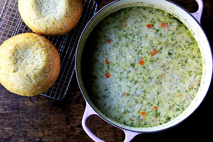 An overhead shot of a large pot of vegetarian cabbage soup aside two loaves of homemade peasant bread. 