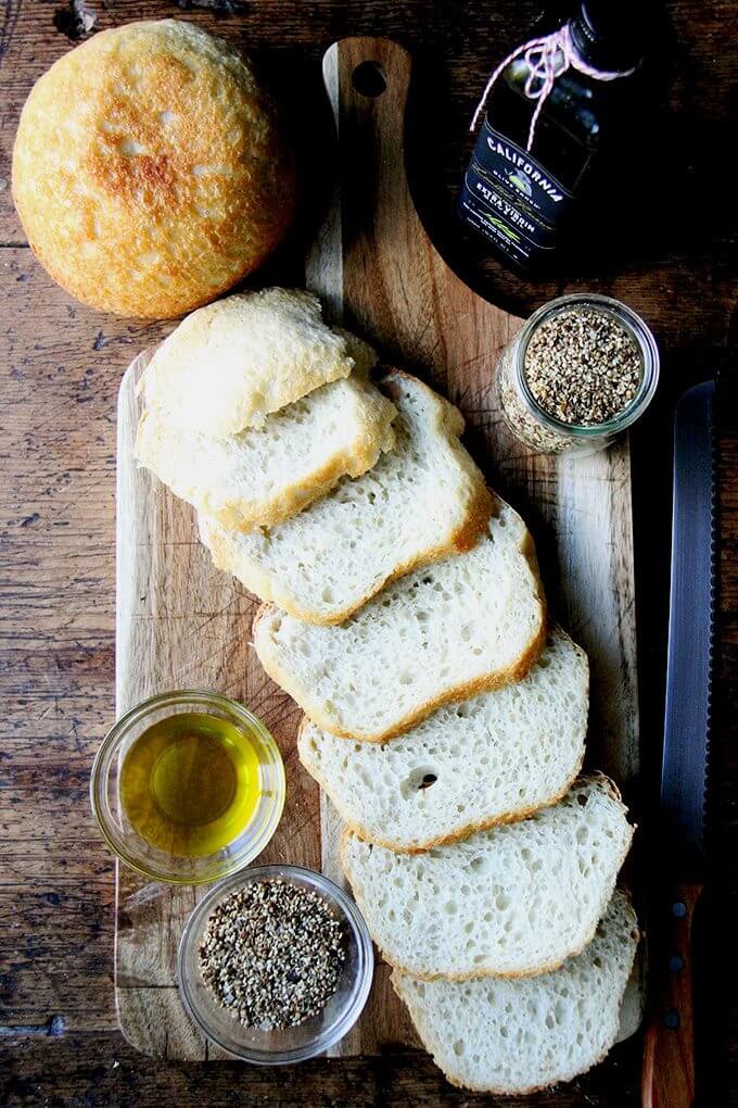 A board with sliced homemade bread aside homemade nut-free dukkah.