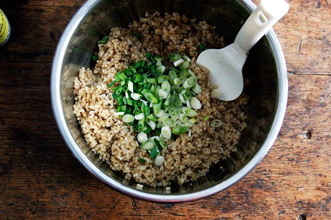 An uncovered Instant pot filled with perfectly cooked Instant Pot brown rice and scallions.