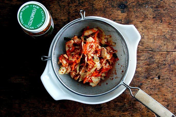 A jar of kimchi draining over a sieve.