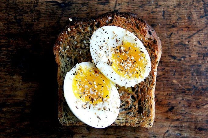 Slice of quinoa-flax bread topped with soft-boiled eggs and dukkah. 