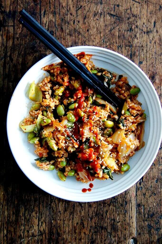 A bowl of kimchi fried rice topped with sriracha.