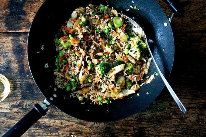 A wok filled with broccoli, shiitakes, kimchi, rice, and edamame.