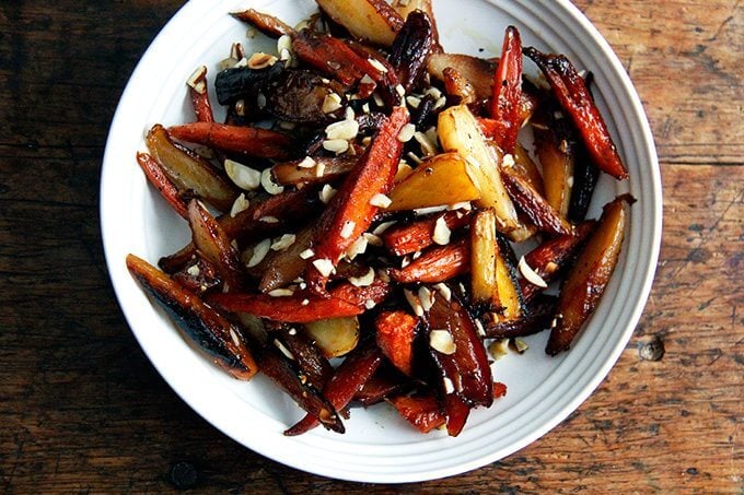 Twice-roasted carrots in a bowl dressed with almonds, salt, and pepper. 