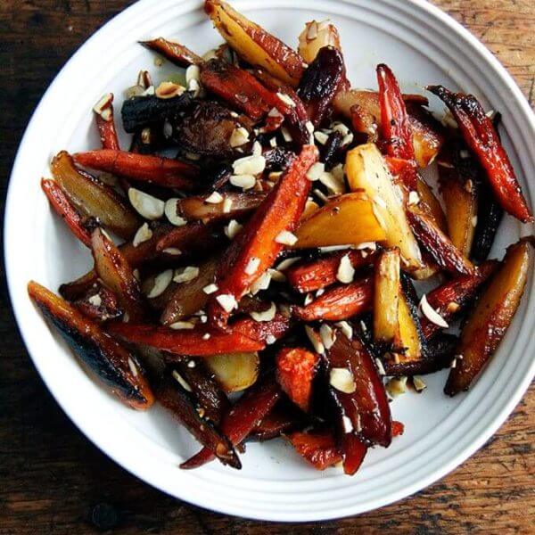 A bowl of roasted carrots with honey and almonds.