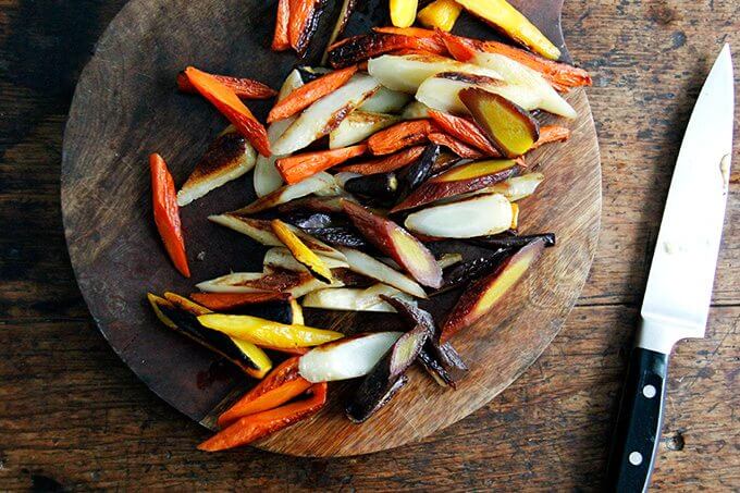 Sliced roasted carrots on a board.