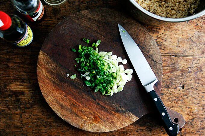 A board with scallions and knife.