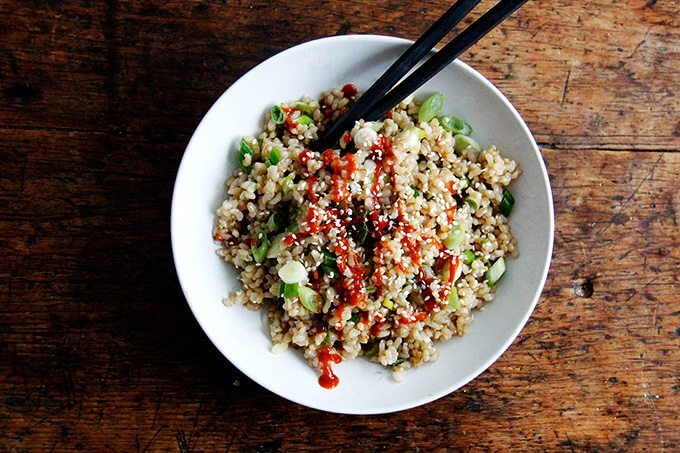 A bowl of perfectly cooked and seasoned Instant Pot brown rice drizzled with Sriracha. 