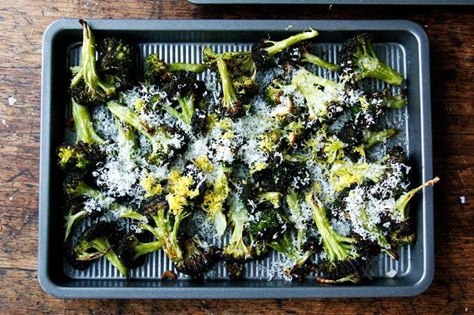 A sheet pan with roasted broccoli covered with parmesan and lemon. 