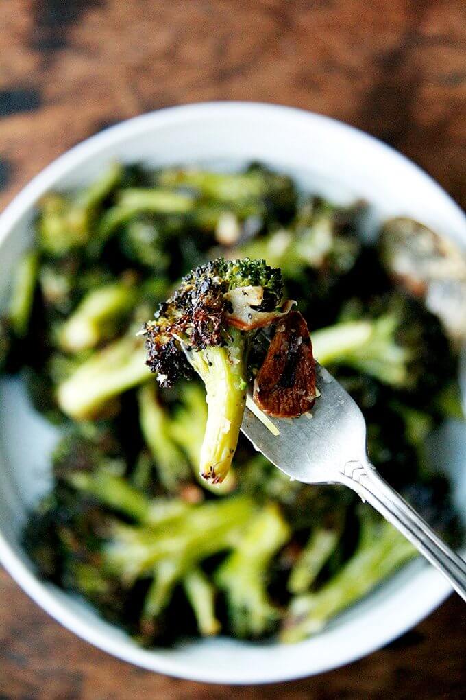 A bite of roasted broccoli with garlic on a fork. 