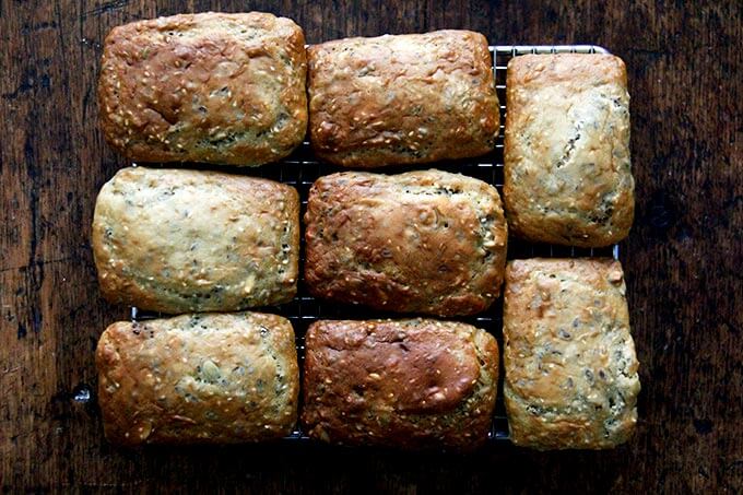 Three seed loaves on a cooling rack.