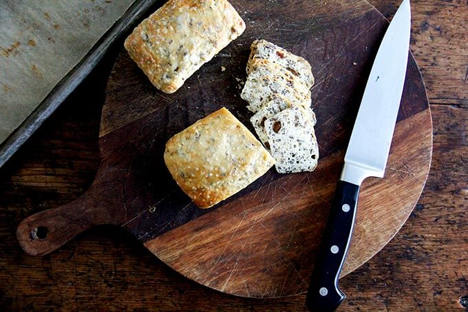 Three seed crackers on a board, sliced thinly. 