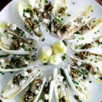 A platter of endive boats with pear, blue cheese, and candied pepitas.