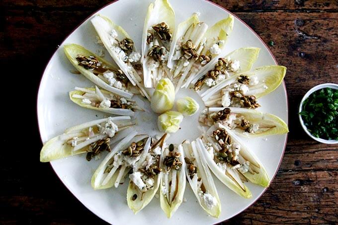A platter of endive boats with slivered pears and blue cheese and candied pepitas.