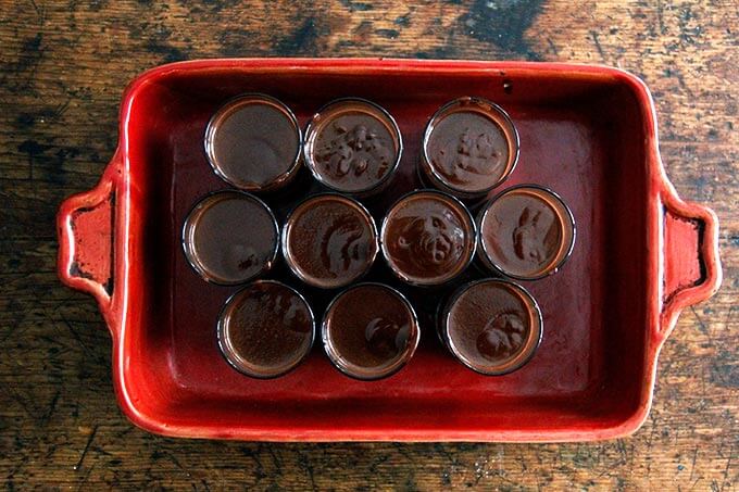 A 9x13-inch baking pan filled with small glasses filled with the chocolate pot de creme.