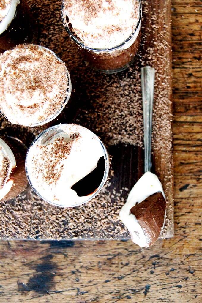 Overhead shot of pots de creme on a board aside a spoon. 