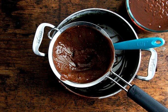 An overhead shot of a strainer set in a liquid measure emptied of the chocolate pot de creme custard.